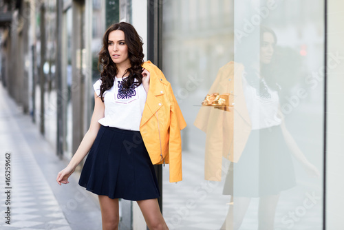 Young brunette woman standing in urban background.