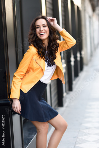 Young brunette woman smiling in urban background.