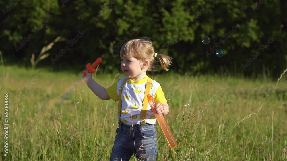 Happy child blowing soap bubbles in summer park. Slow motion. Happy child blowing soap bubbles in summer park. Slow motion.