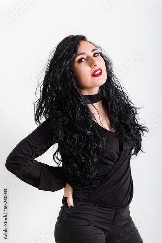 young turkish brunette woman wearing in black clothes poses on white background in studio