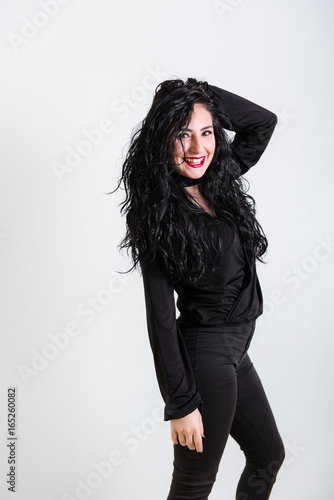 smiling young turkish brunette woman wearing in black clothes poses on white background in studio