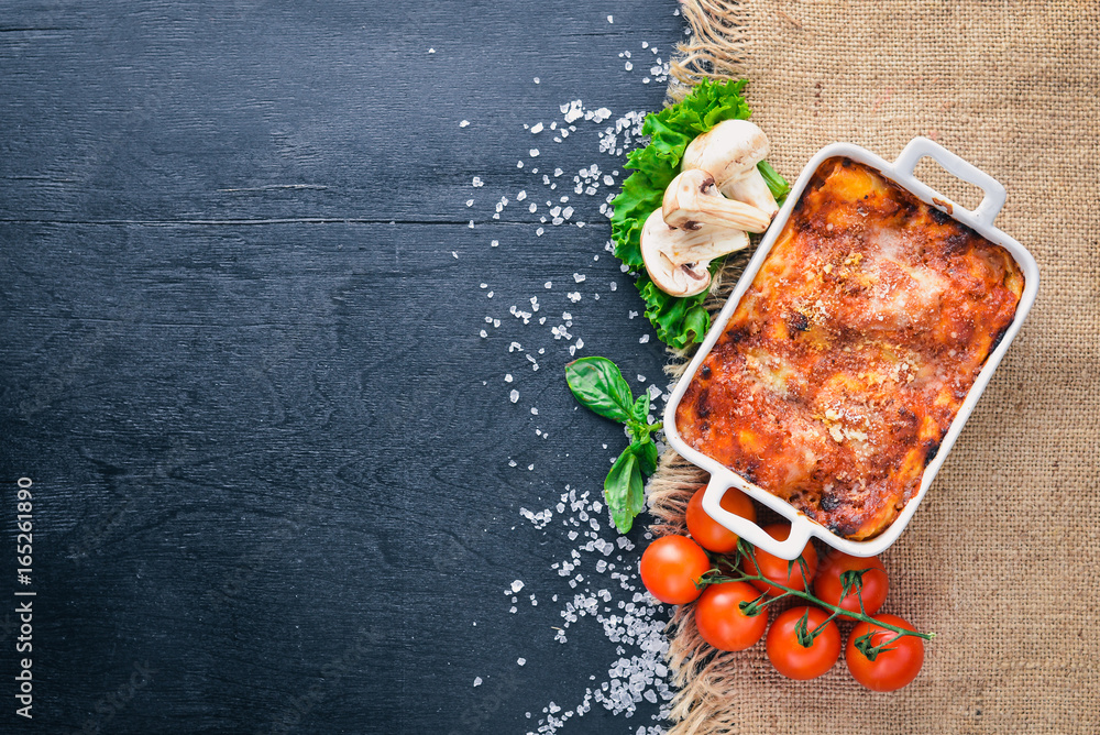 Lasagna with vegetables and cheese. On a wooden background. Top view. Free space for your text. - obrazy, fototapety, plakaty 