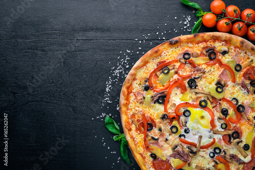 Pizza with vegetables. On a wooden background. Top view. Free space for your text.
