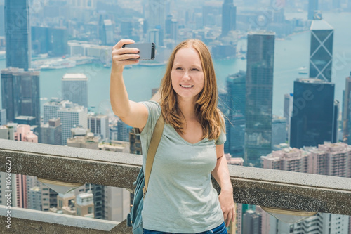 Canvas Print Hong Kong Victoria Peak woman taking selfie stick picture photo with smartphone enjoying view over Victoria Harbour