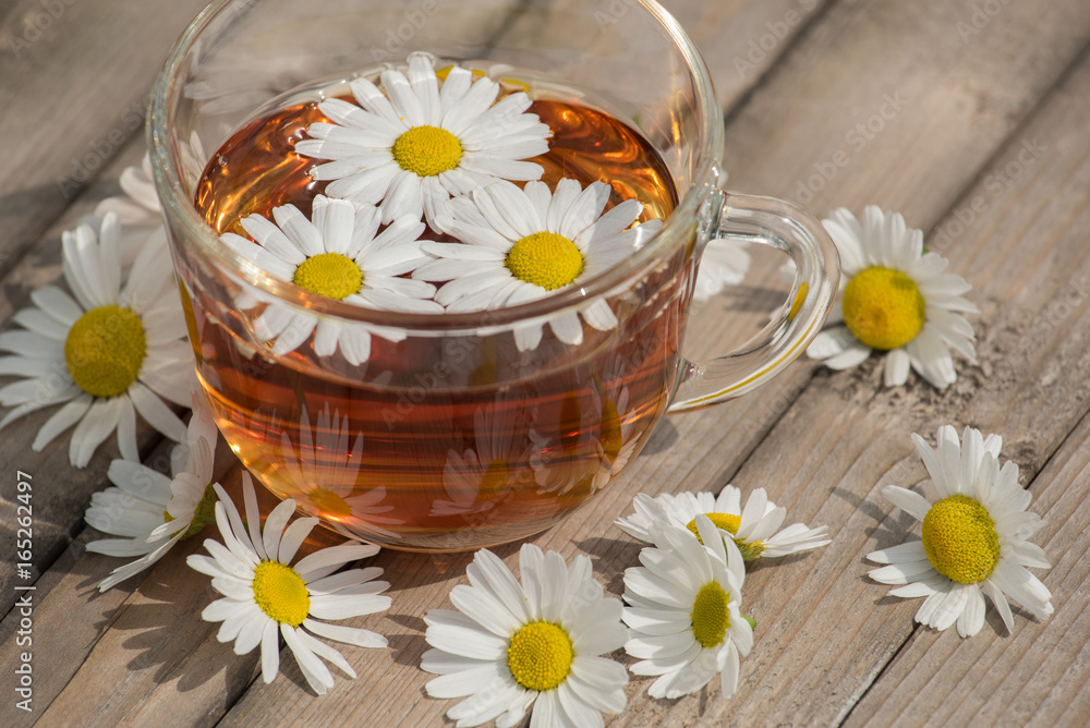Herbal tea with chamomile on a wooden table on a summer sunny morning Herbal tea with chamomile on a wooden table on a summer sunny morning