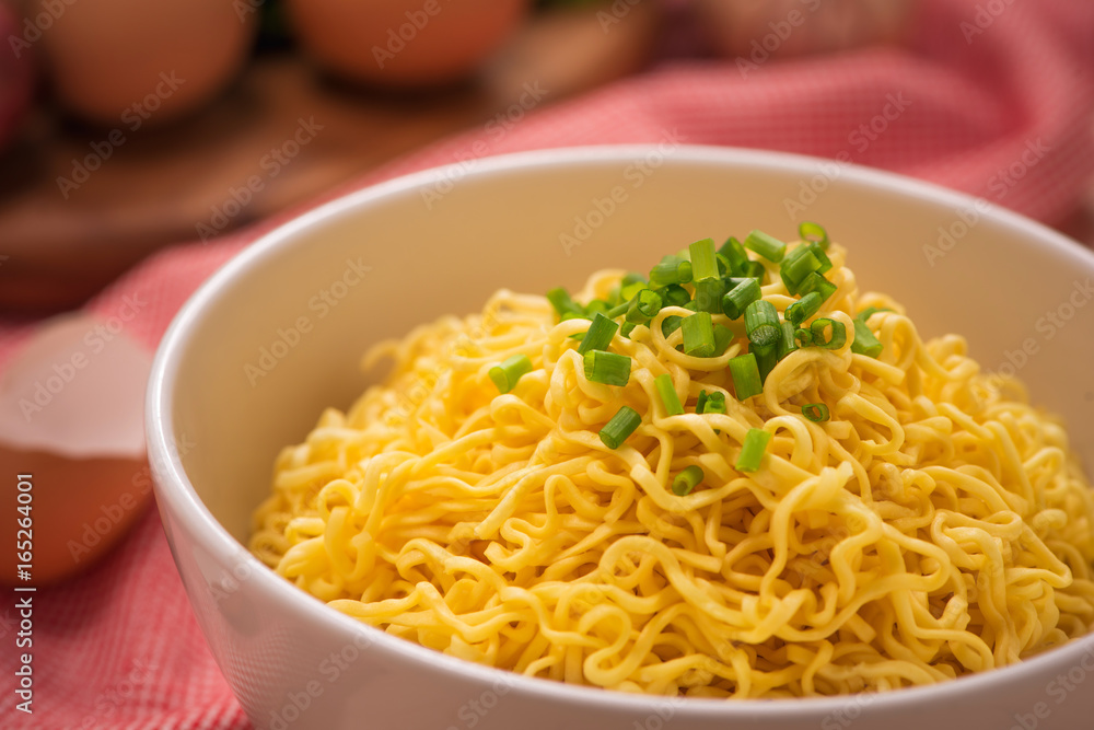 Instant noodles in bowl with vegetables on wood background Instant noodles in bowl with vegetables on wood background