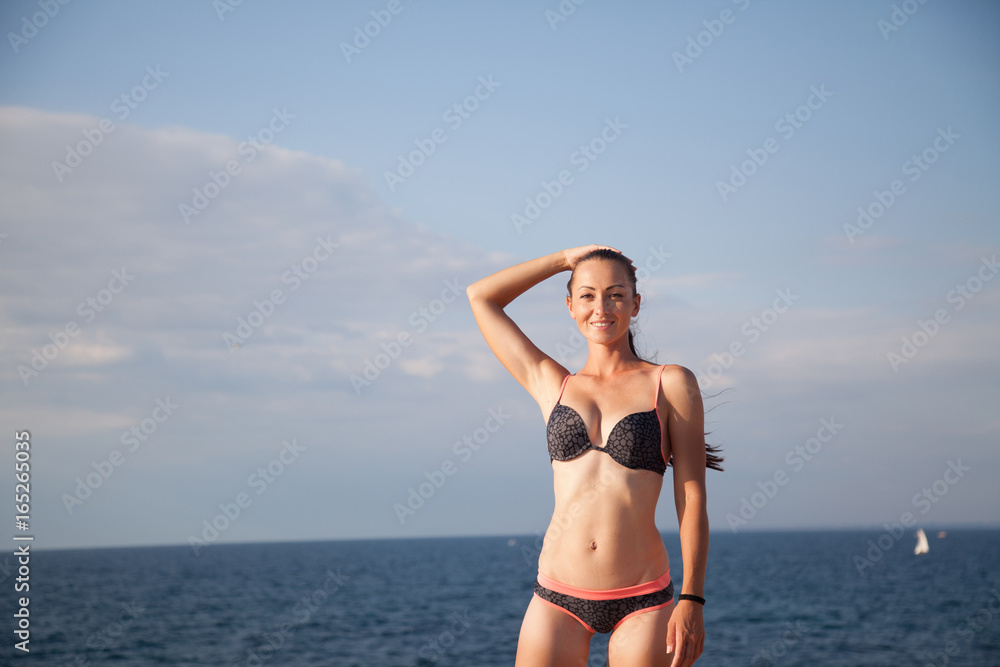 girl in bathing suit sunning on the beach by the sea