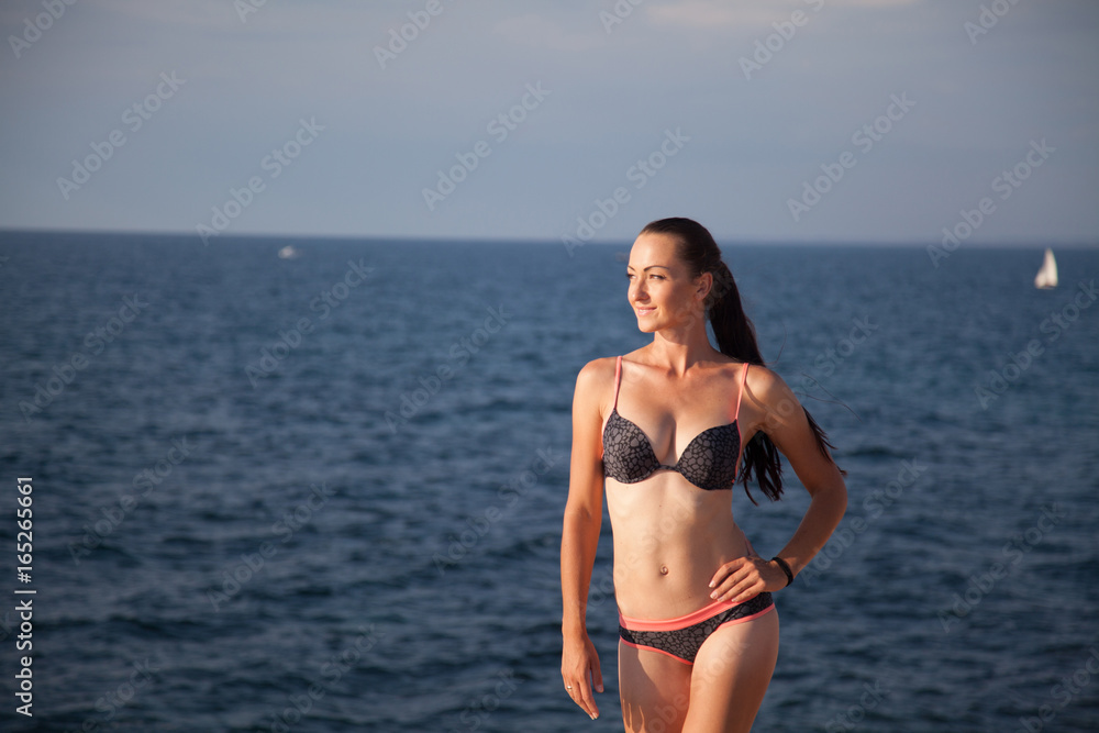 girl in bathing suit sunning on the beach by the sea