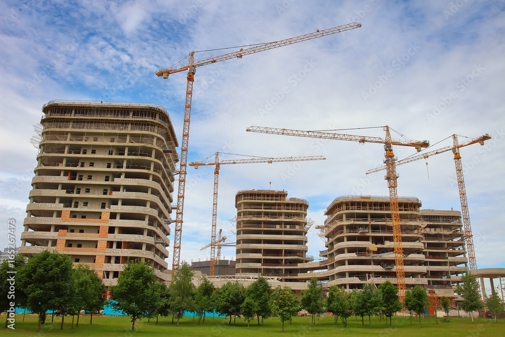 Construction of new residential area. Construction industrial cranes, gray monolithic houses made of concrete. Concept of construction. Construction of new residential area. Construction industrial cranes, gray monolithic houses made of concrete. Concept of construction.