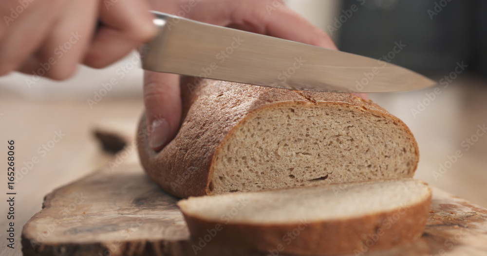 young female hands slicing rye wheat rustic bread on cutting board young female hands slicing rye wheat rustic bread on cutting board