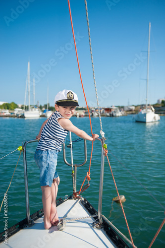 smiling little boy captain aboard luxury boat during the ocean cruise