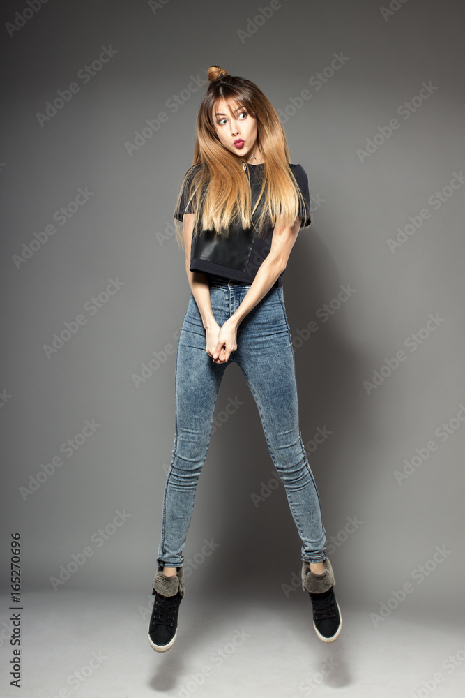 Happy attractive joyful dance model is jumping in studio, isolated on gray background Happy attractive joyful dance model is jumping in studio, isolated on gray background