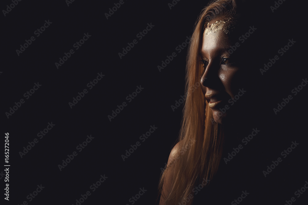 Fashion photo of a beautiful young woman. Beauty gold portrait girl on black background.