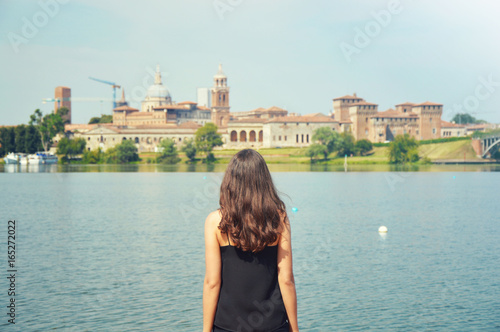 Young woman travel to Europe. Happy Tourist in Mantua looking at cityscape. Cheerful brunette girl traveler enjoy italian landscape in Mantua popular travel place in Italy.