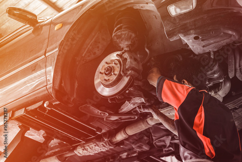 Car lifted in automobile service for fixing. Professional  mechanic male in garage automobile checking. Auto service