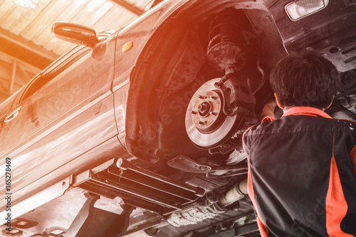 Car lifted in automobile service for fixing. Professional  mechanic male in garage automobile checking