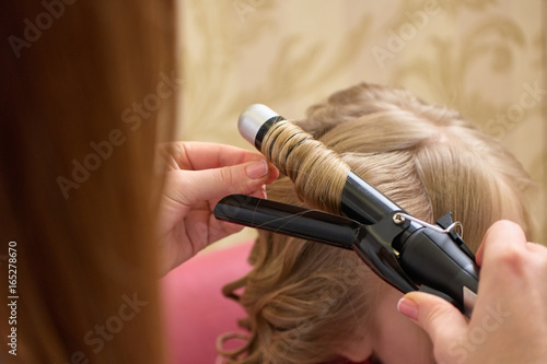 Hands using curling iron. Hair styling tool close up. How to make hair curly.