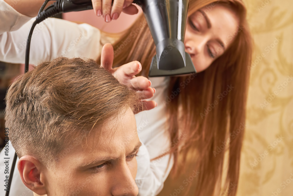 Fototapeta premium Barber drying hair of client. Male haircut, close up.