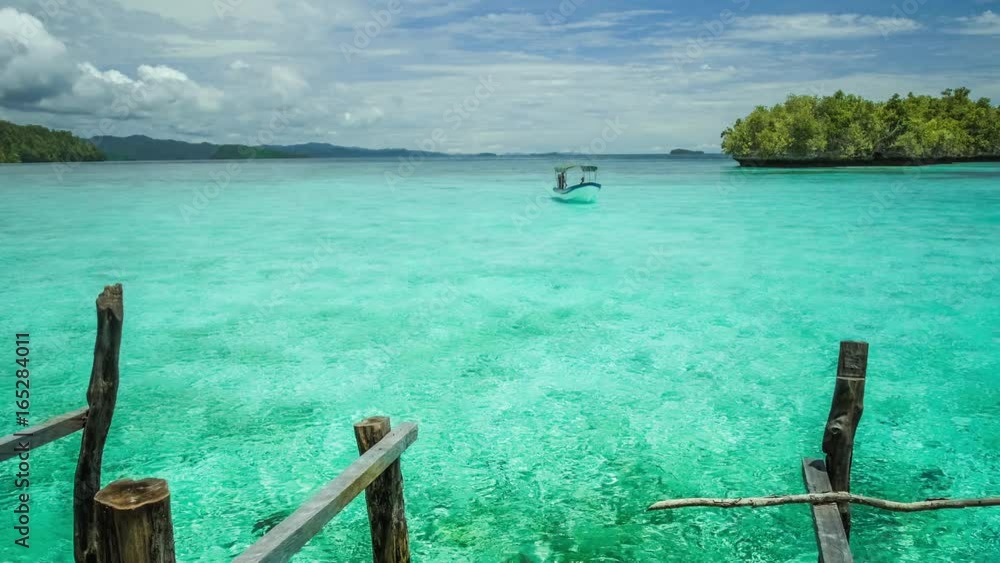 Blue lagoon with pure clear water and clouds and small island in background. Small boat comming in. Blue lagoon with pure clear water and clouds and small island in background. Small boat comming in.