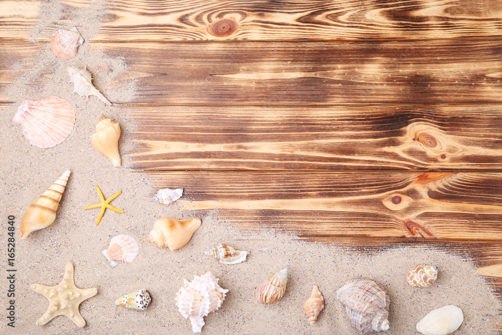 Seashells with beach sand on brown wooden table Seashells with beach sand on brown wooden table