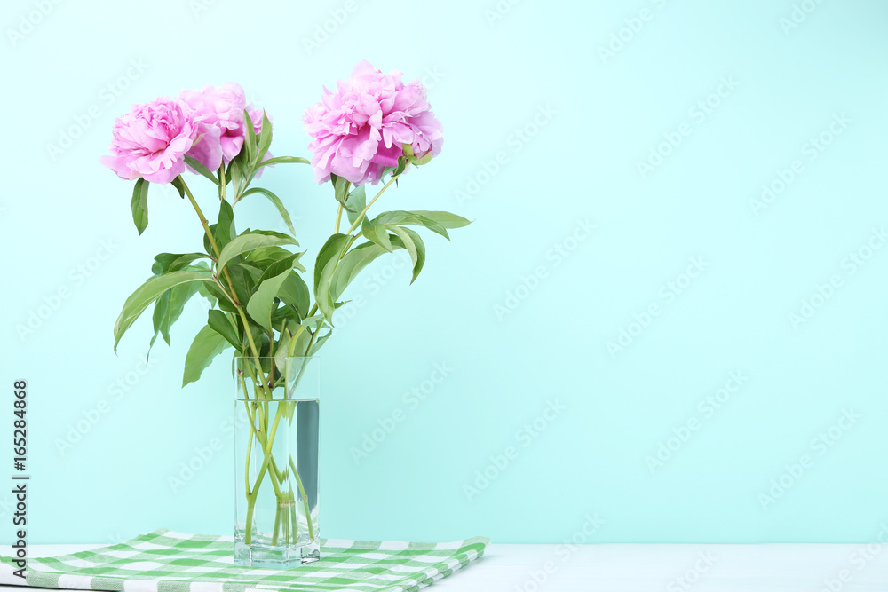 Bouquet of peony flowers in vase on mint background Bouquet of peony flowers in vase on mint background