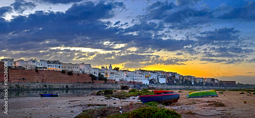 historical part of the Moroccan city on a sunset, settles down on the river bank, several fishing boats in the foreground