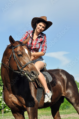  young cowgirl horseback riding in sunny day