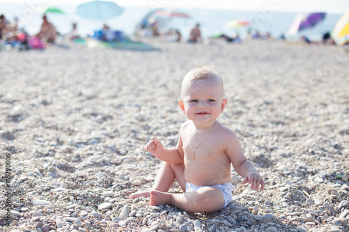 little baby boy playing on the beach near the sea photo