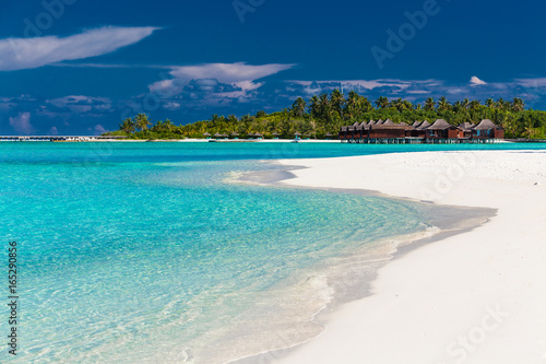Over water villas in Maldives and a white beach with palm trees