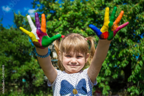 Cute girl showing her hands painted in bright colors. Art and painitng concept