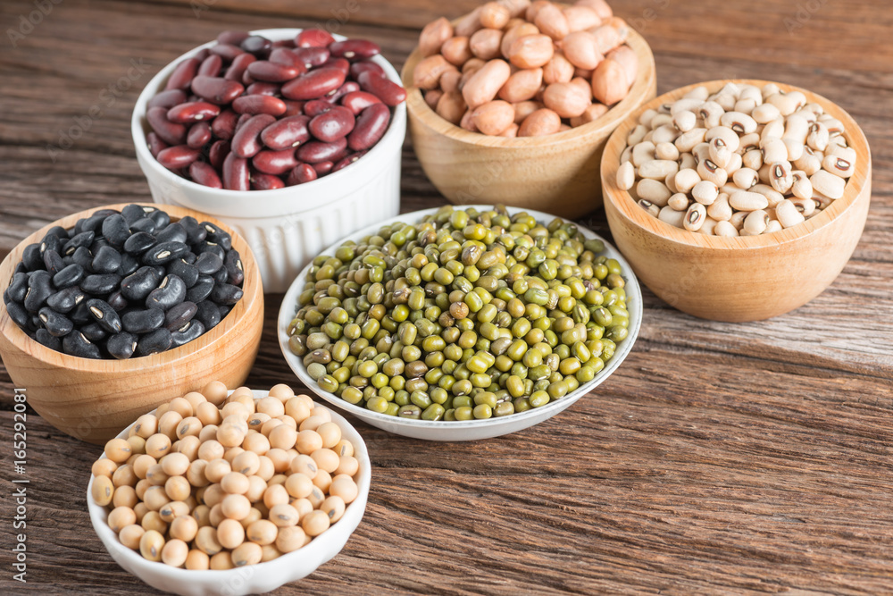 Mixed beans in wood bowl on wood background.