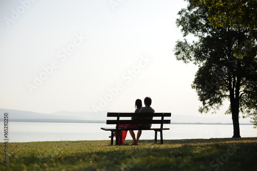 Couple in love sitting on a bench by the lake