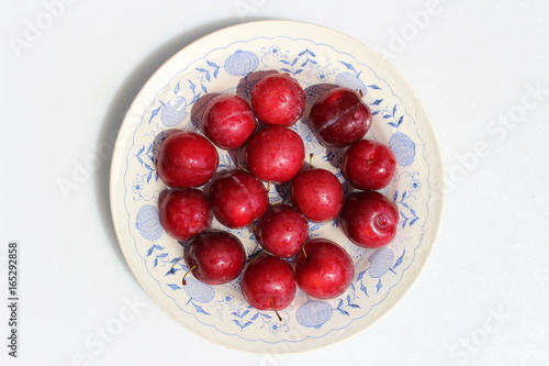 Red plums on a plate with a pattern