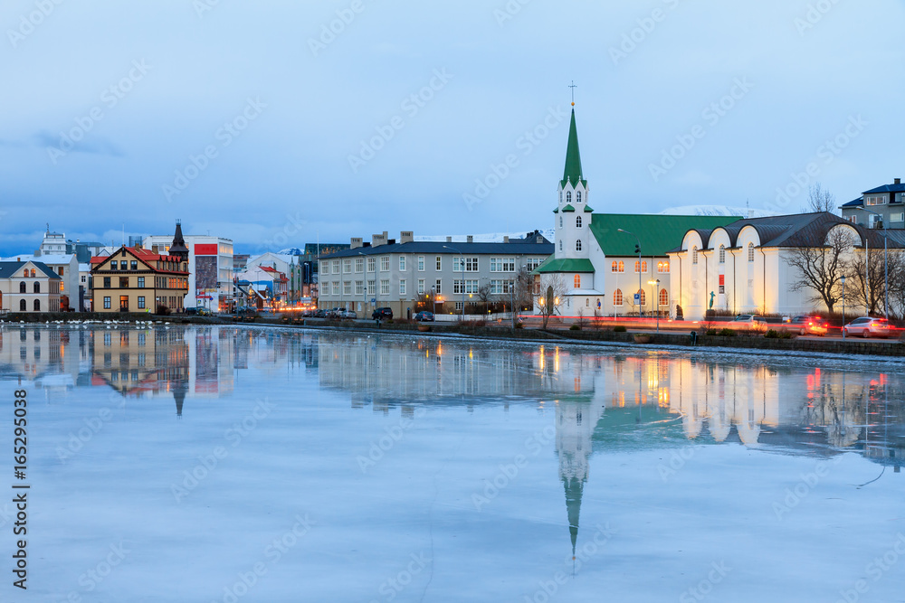 Beautiful reflection of the cityscape of Reykjavik and the Free church in lake Tjornin at the blue hour in winter