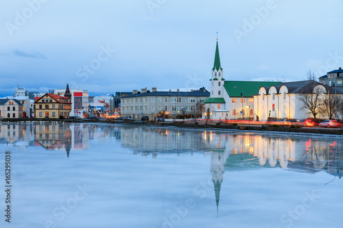 Beautiful reflection of the cityscape of Reykjavik and the Free church in lake Tjornin at the blue hour in winter