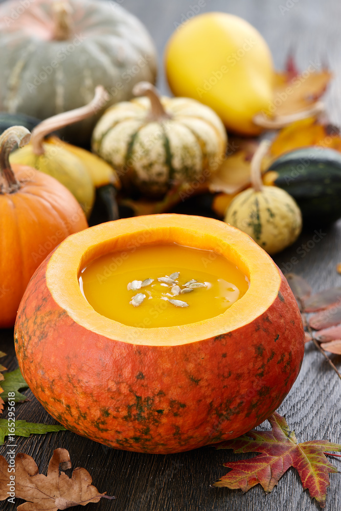 Fall pumpkin soup in big decorative pumpkin on dark wooden background Fall pumpkin soup in big decorative pumpkin on dark wooden background