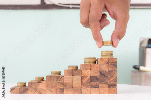 Wooden block stacking as staircase level with golden coins on top, business growth concept