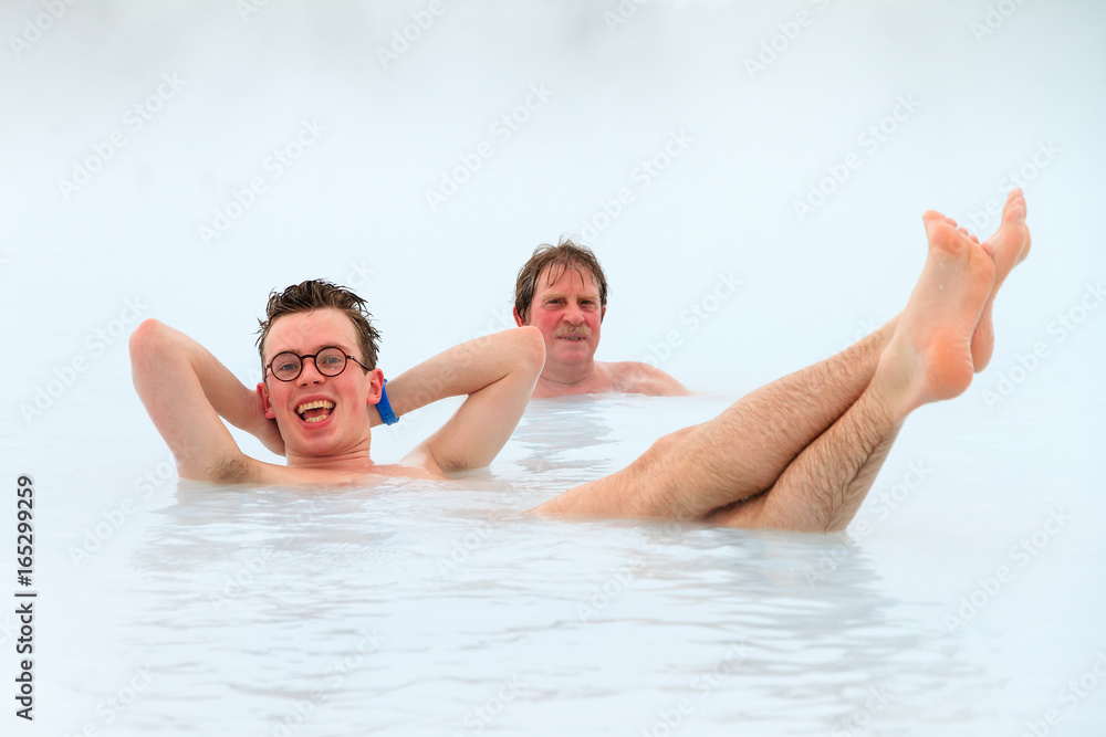 Young men relaxing in blue waters from a hot spring with sulfur and silica in Iceland Young men relaxing in blue waters from a hot spring with sulfur and silica in Iceland