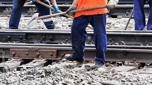 Railwayman in uniform with shovel in hands repairs railway track.