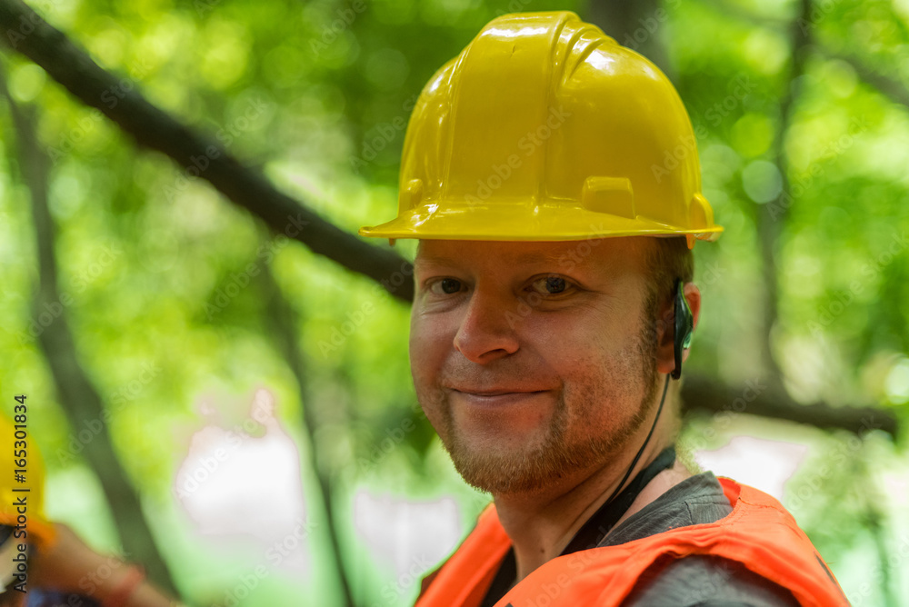 An engineer standing among trees with a yellow helmet An engineer standing among trees with a yellow helmet