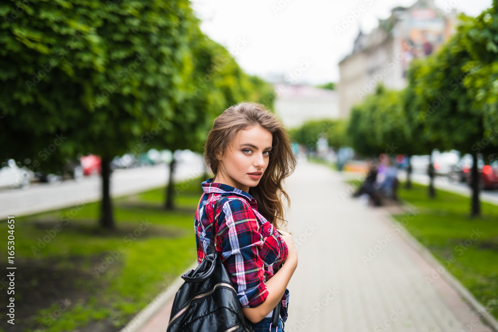 Fashion portrait trendy young woman with backpack in the city simmer