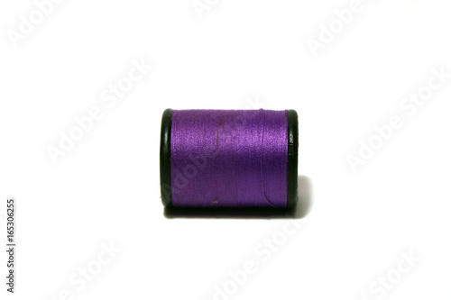 Purple thread in the black thread roll on white background. Prepare to use for sewing garment.