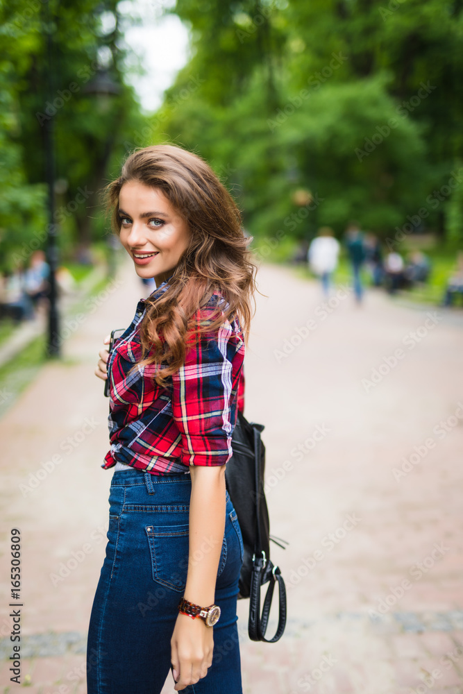 Summer sunny lifestyle fashion portrait of young stylish hipster woman walking on street