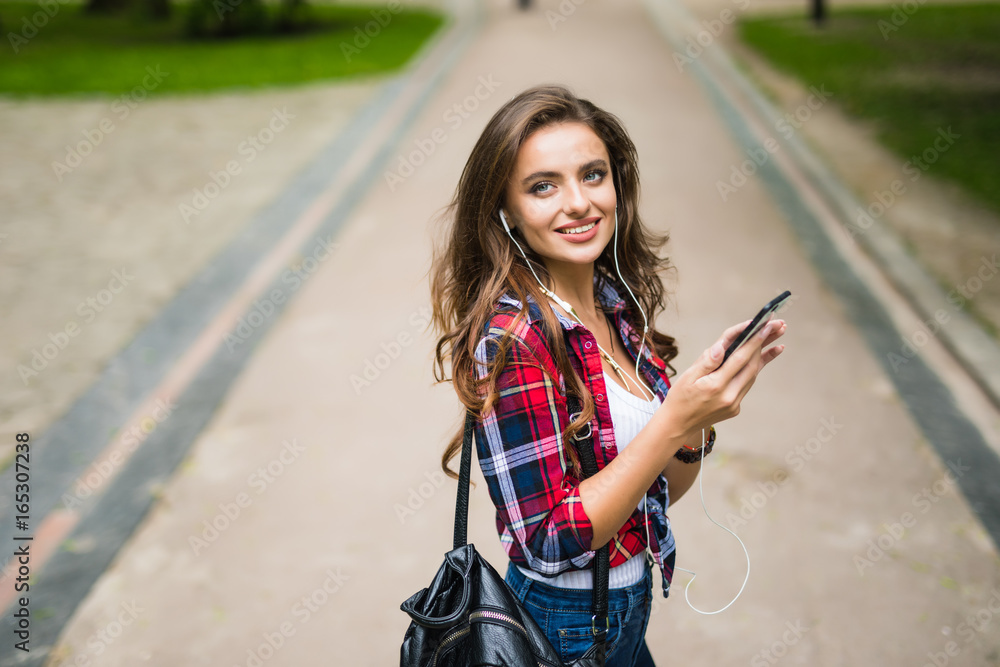 Happy beautiful young caucasian high school girl with green smart phone outdoors on sunny
