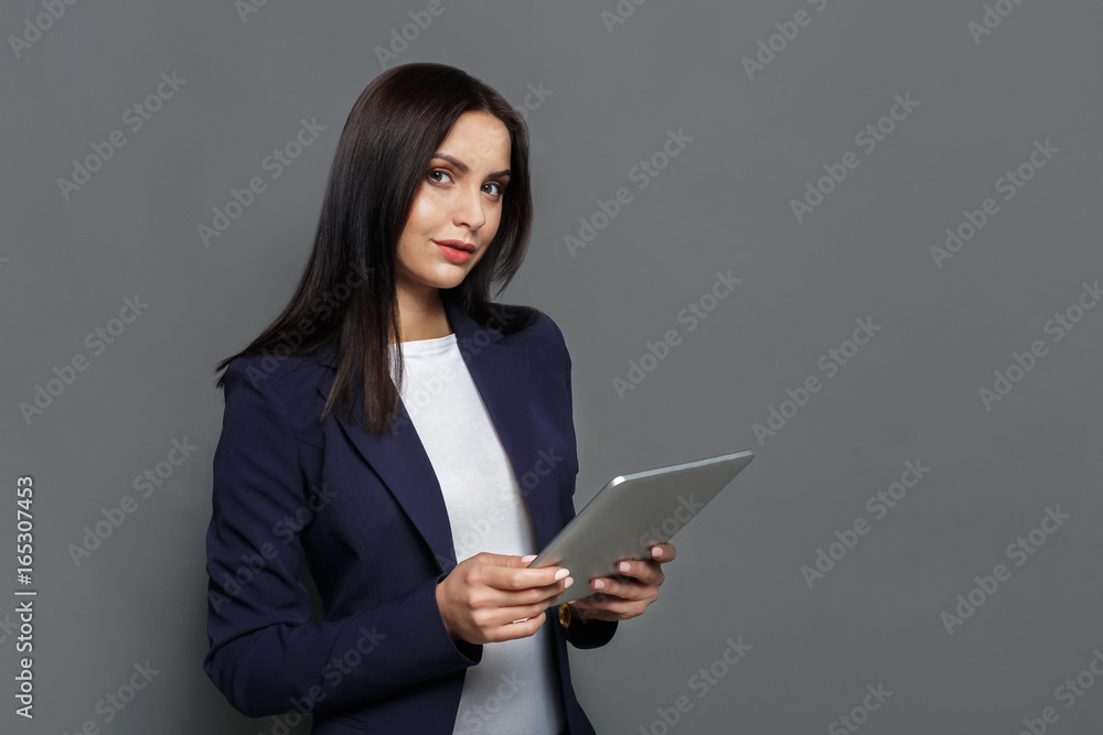 Concentrated woman with tablet on gray background