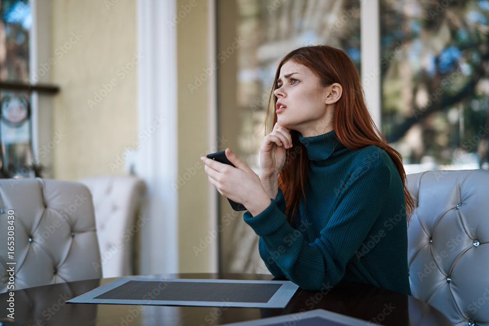 Beautiful young woman sitting in a cafe on a street in the city