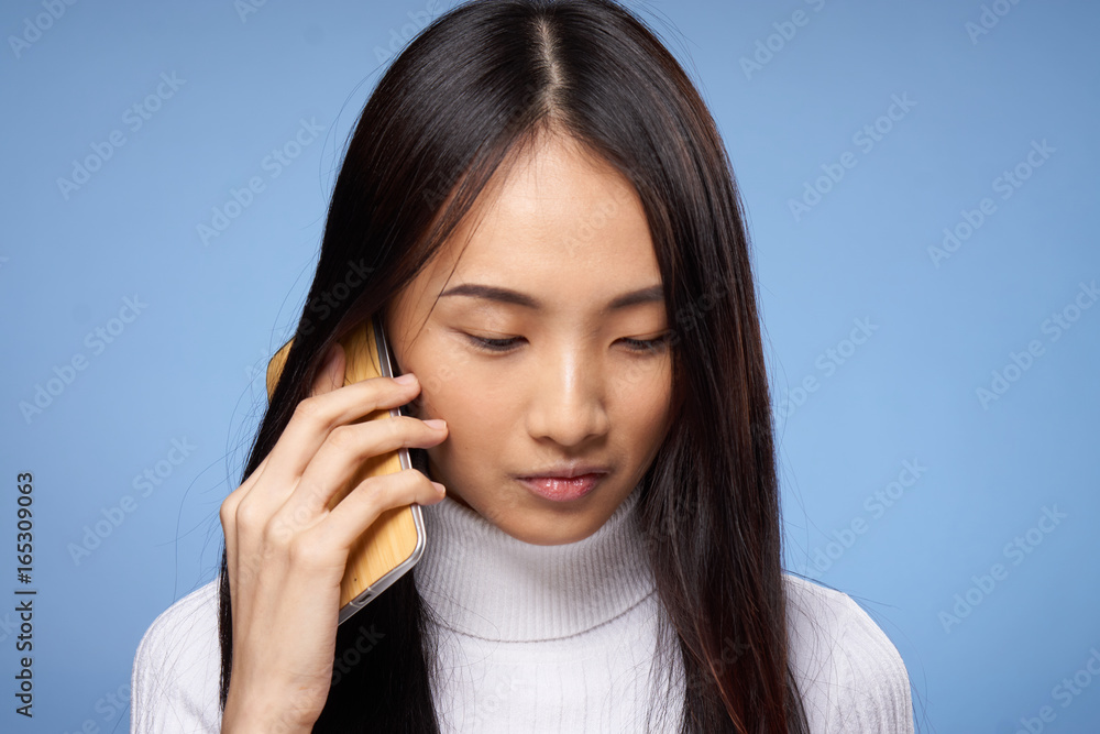 Beautiful young woman on a blue background calls on the phone, asian Beautiful young woman on a blue background calls on the phone, asian