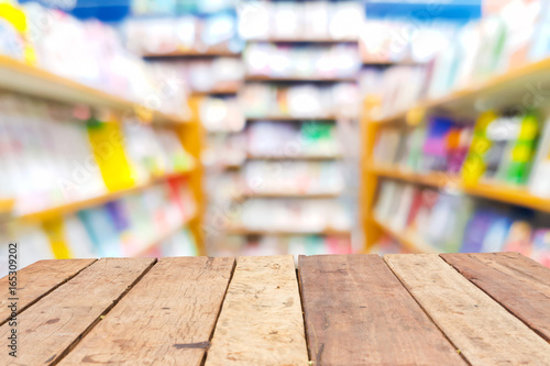 perspective wooden board empty table in front of blurred background of shelves in bookstore or library,can be used for display or montage your products. Mock up for displaying product.