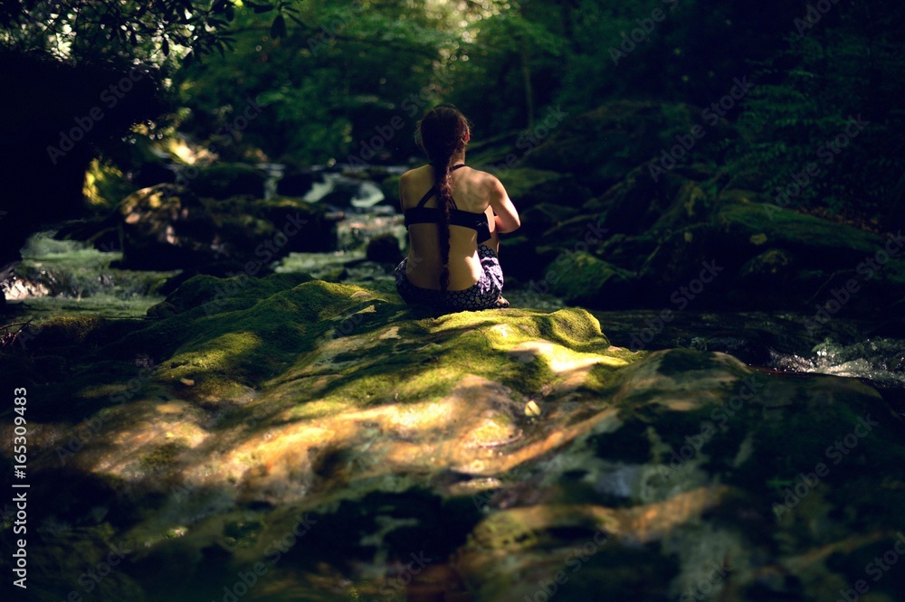 Young woman sitting by a river Young woman sitting by a river