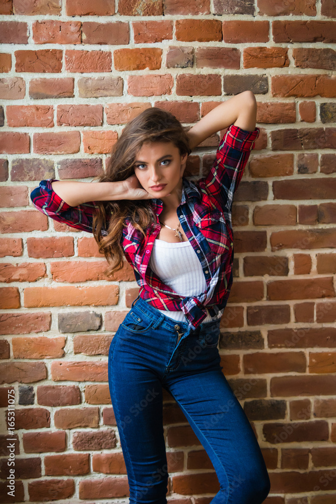 Beautiful young woman stands near the brick wall Beautiful young woman stands near the brick wall